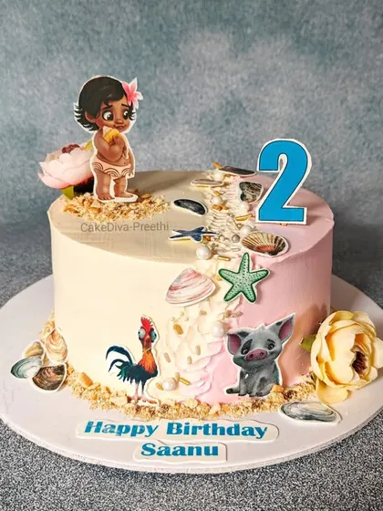 A sweet Moana-themed cake for a second birthday. This design uses a palette knife to create a two-tone background, decorated with edible character prints and shell details.