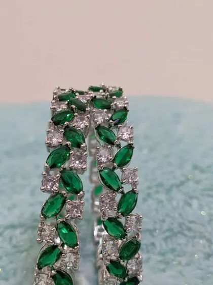 A pair of AD bangles with a leaf-like marquise-cut emerald stone design.