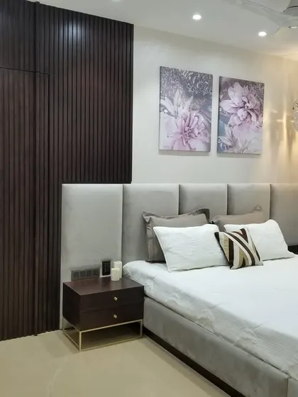 We love creating seamless designs with hidden elements. In this cozy bedroom, the bathroom door is cleverly camouflaged within a dark wood fluted wall panel, making the room feel more spacious and uncluttered.