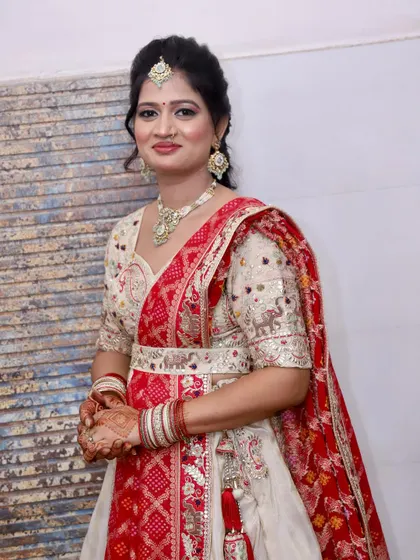 A beautiful guest in a traditional white and red lehenga, her makeup is subtle and elegant.
