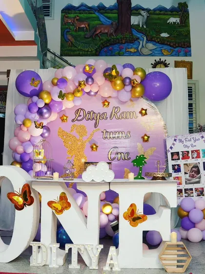 A simple and coustamised balloon decoration for Ditya Ram's first birthday at home. The purple and gold color scheme, "ONE" table, and milestone board make it a personal and special celebration.