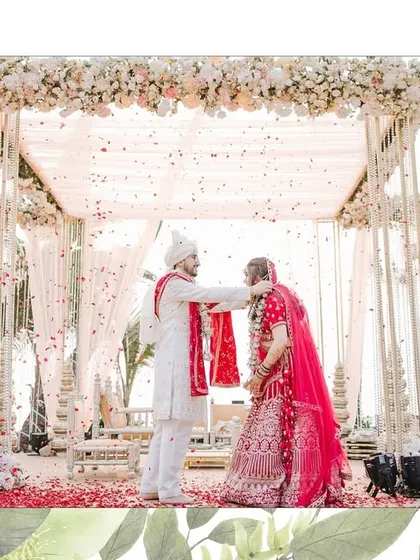 A beautiful Varmala moment at a beachside wedding. The groom places the garland on his bride under a stunning floral mandap.