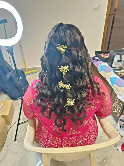 A half-up hairstyle with curls, adorned with sprigs of baby's breath. This is a delicate and romantic look, perfect for a daytime event.