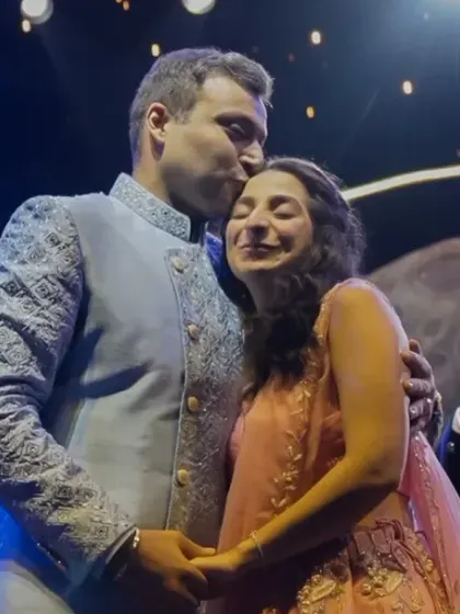The groom kisses his bride on the forehead as they are cheered on by family and friends after their engagement ceremony.