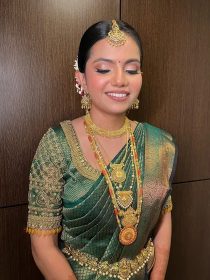 A Tulu princess on her special day. This South Indian bride is adorned in a beautiful green silk saree, with makeup featuring a classic liner, flushed cheeks, and a nude lip.