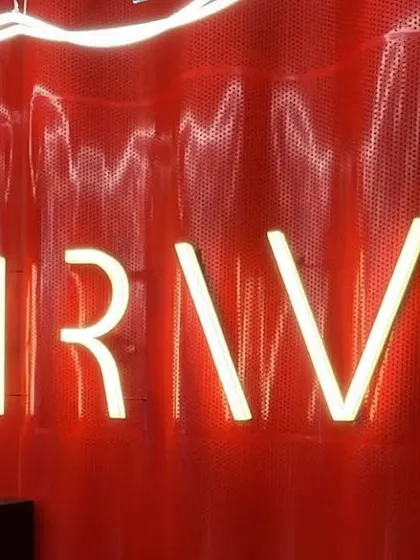 A close-up of the neon "THRIVE" sign against the red corrugated wall. This branding element is a key focal point, reinforcing the gym's identity with a modern, energetic glow.