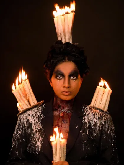 A direct, haunting look from the candle-themed fantasy shoot. The white eye contacts and dripping wax makeup create a powerful and eerie character.