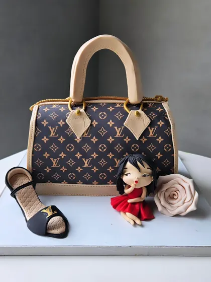 A closer look at the sculpted Louis Vuitton bag cake. The texture, logo, and accompanying edible shoe and figurine make it a complete fashion statement.