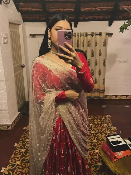 A mirror selfie capturing the full glory of this custom red 'Laal' lehenga. It's paired with a delicate, embellished dupatta, making it a perfect outfit for a Sangeet or wedding reception.