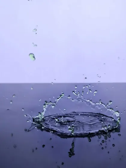 The moment a droplet hits the water's surface, captured in a stunning crown-shaped splash. This type of high-speed photography requires perfect timing and adds a dramatic flair to any liquid product.