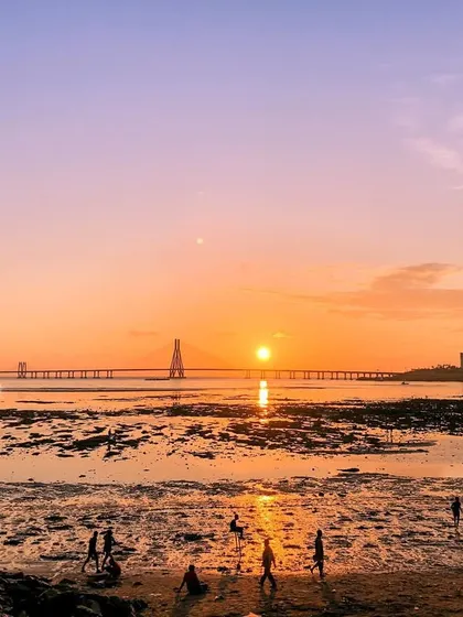 A view of the sunset at a Mumbai beach with the Bandra-Worli Sea Link in the background.