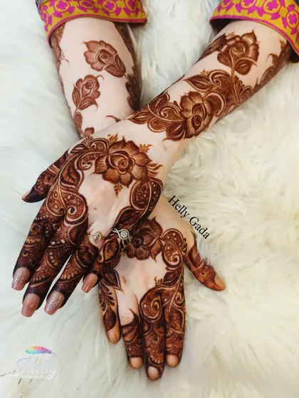 A gorgeous example of a full-coverage floral design after the henna paste has been removed. The rich, dark stain highlights the intricate details of the roses and vines climbing up the arm.