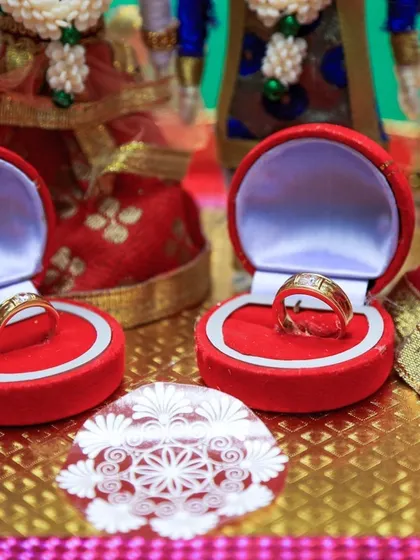 A detail shot of the wedding rings, placed in their boxes in front of traditional dolls.