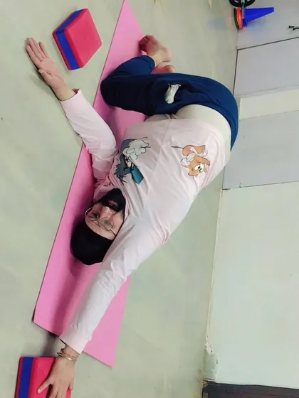 A student uses yoga blocks to support a deep twisting stretch. Props are for everyone and help in achieving correct alignment and preventing injury, especially in complex poses.