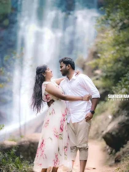 A close-up, happy moment between a couple with a waterfall in the background.