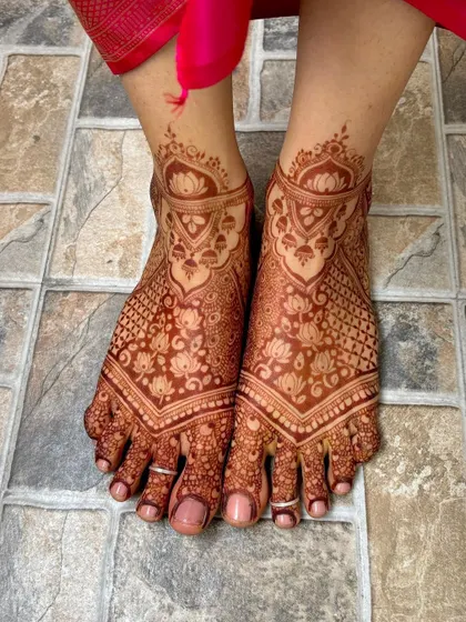 The beautiful, rich stain of a full bridal feet mehendi, featuring lotus and paisley patterns.