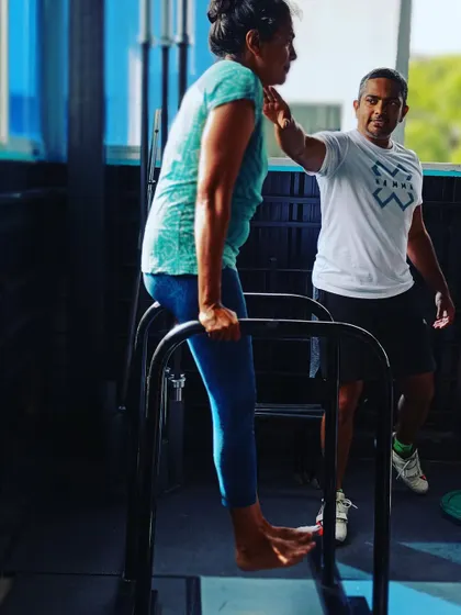 Our coaches provide tactile cues to ensure proper form and muscle engagement. Here, a coach guides a member through a dip, helping her maintain a strong, stable position.