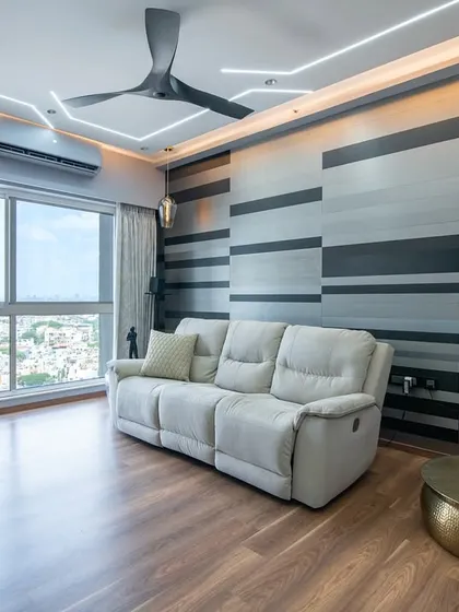 This living space at SNN Clermont features an understated luxury with a calming blue-toned theme. The gradient-striped feature wall adds depth and movement, complementing the plush recliner sofa.
