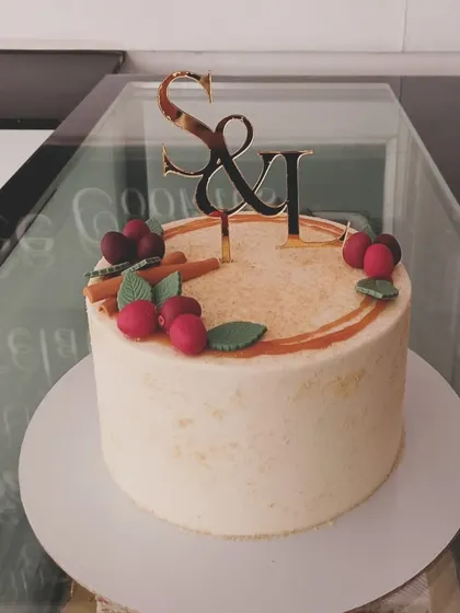 A simple and sweet single-tier cake for an intimate anniversary or engagement. It features a rustic textured frosting and is topped with a custom "S&I" acrylic topper and delicate fondant berries and cinnamon sticks.