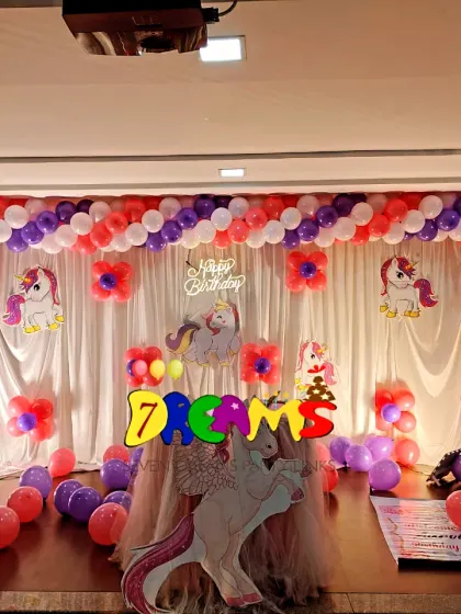 A simple unicorn theme for a stage setup. I used a white curtain backdrop with a large balloon arch in purple and red, along with several unicorn props.