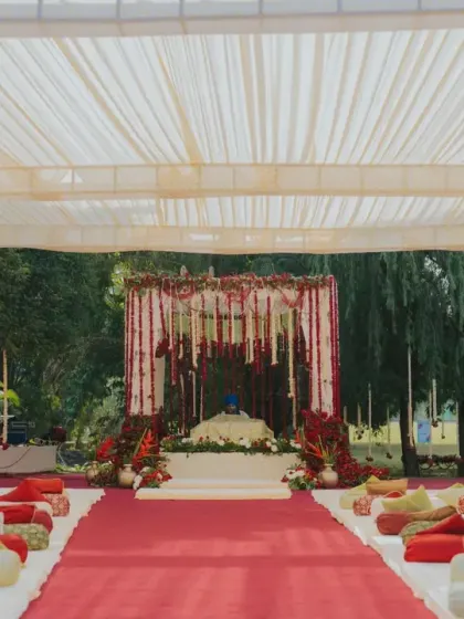An Anand Karaj ceremony set against a backdrop of apple red and fresh blooms. The decor respects tradition with low seating on plush cushions, creating an intimate and serene space for the Sikh wedding rituals.