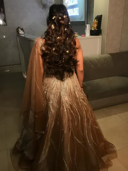Here is the back view of the hairstyle from the previous image. The soft curls and scattered flowers create a beautiful, ethereal look that is perfect for a romantic evening function.