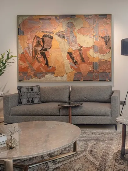 Here, a simple grey sofa serves as a quiet foundation for a vibrant piece of abstract art. The furniture is intentionally understated to allow the artwork to shape the room's emotional tone, demonstrating our belief that art is an integral part of the home's architecture.