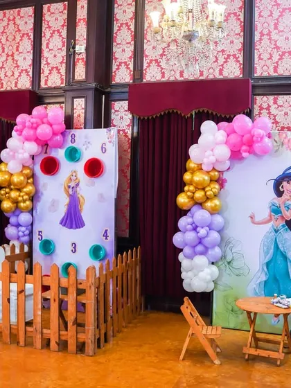 A princess-themed area with a bean toss game and a tattoo station, featuring backdrops of Rapunzel and Jasmine.
