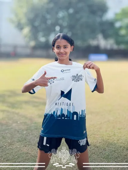 Proudly pointing to the crest. This player shows her commitment to the team, a symbol of the unity and identity we build at The Dream Team.