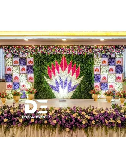 This baby shower stage features a unique floral mosaic backdrop with a lotus motif at the center. The purple and white color scheme creates a serene and elegant atmosphere.