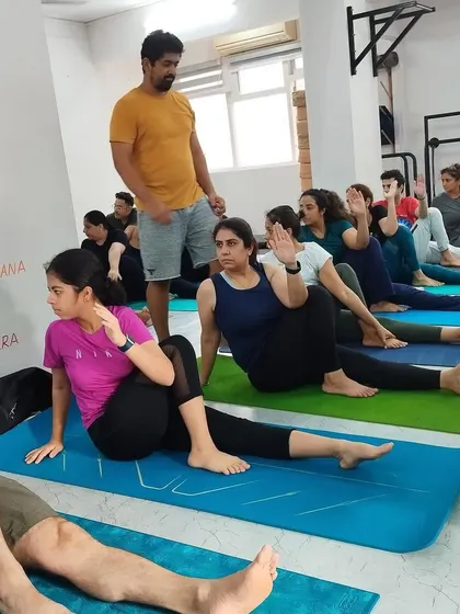 An instructor observes the class during a seated spinal twist, ensuring everyone maintains safe and effective alignment.