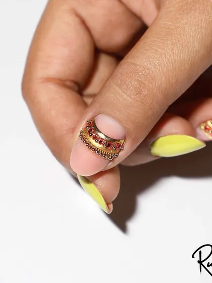A custom jewelry design created for a client. This piece features a band of red and gold crystals along the cuticle, adding a touch of royal elegance to the nail.