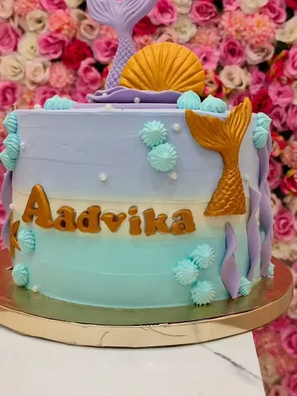 This 2 kg Dutch Truffle mermaid cake features a beautiful gradient of purple and teal. The golden mermaid tails and name add an elegant touch to the underwater theme.