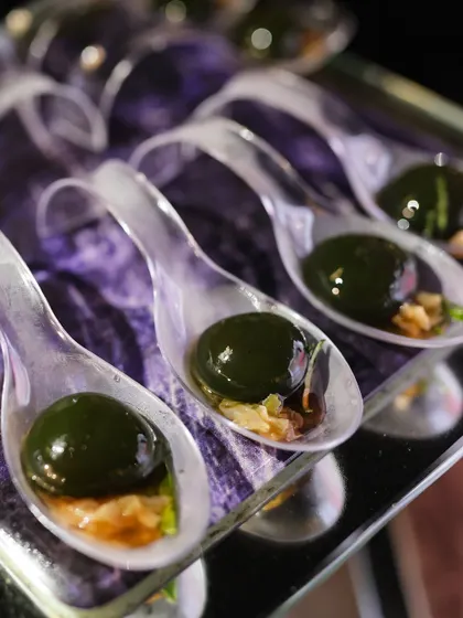 These dark green molecular spheres offer another unique flavor experience, served elegantly on individual spoons for a sophisticated tasting.