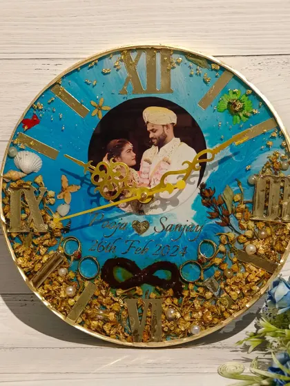 A vibrant blue clock with a beachy, underwater feel. This piece includes a couple's photo, preserved flowers, and seashell details, perfect for a destination wedding memory.