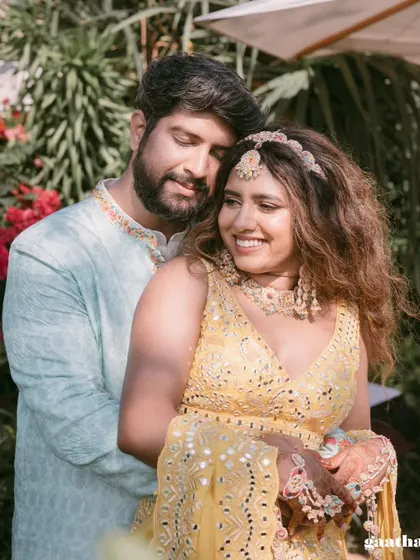 A tender moment shared between the couple during their outdoor Haldi ceremony, surrounded by lush tropical plants.