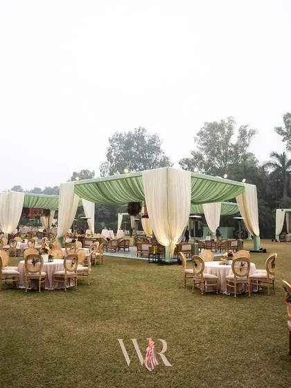 A wide shot of the outdoor Mehndi setup, showing the multiple tented areas for dining and lounging. The consistent color palette of green and cream creates a cohesive and elegant look across the large space.