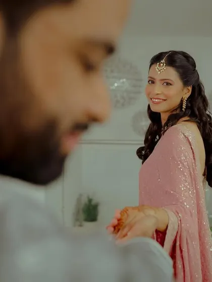 A beautiful over-the-shoulder shot capturing the bride's happy expression as the groom slips the engagement ring on her finger.