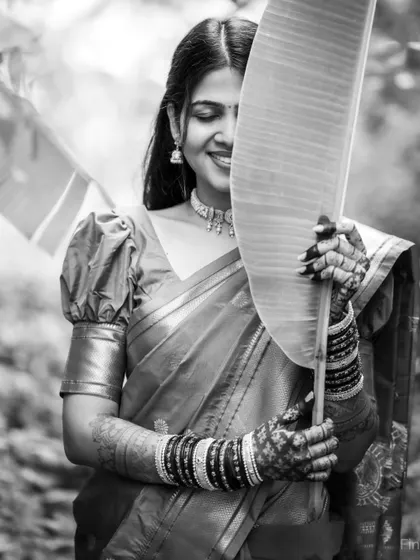 A creative black and white portrait of the bride, using a large leaf to create a playful and artistic composition.