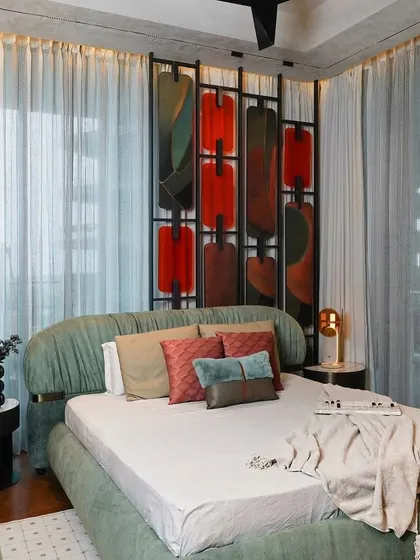 A wider view of the Matoshri Residence master bedroom, showing the full effect of the sculptural headboard, sage-green bed, and sheer drapes. The ambient lighting from the pendant lamps adds warmth and intimacy.