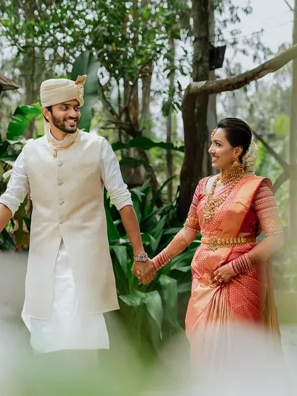 A romantic walk through a beautiful garden venue. This shot captures the couple hand-in-hand, framed by nature, creating a serene and timeless portrait.
