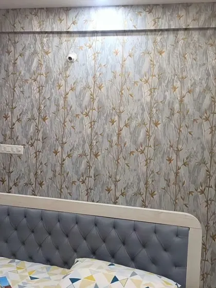 A bedroom wall with a bamboo-like pattern in gold on a textured grey background. This design combines natural and modern elements for a unique look.