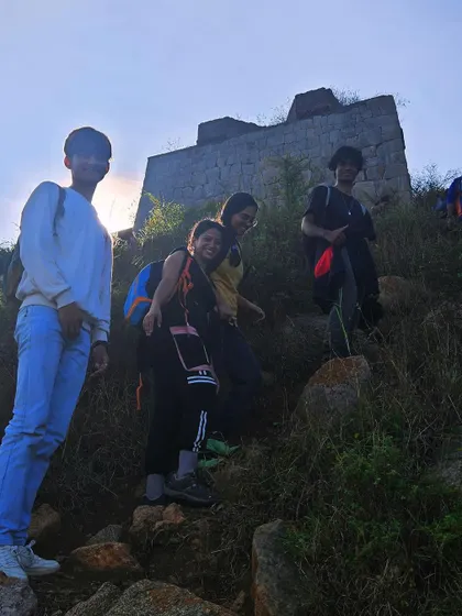 Trekkers making their way up a trail with ancient fort ruins in the background. Our treks often include elements of history and heritage.