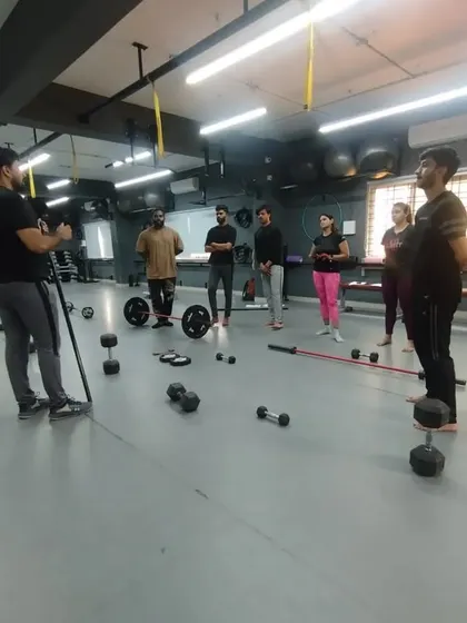 A master trainer demonstrates correct form while students observe. Practical classes like this, focusing on weightlifting and equipment use, are a core part of our curriculum.