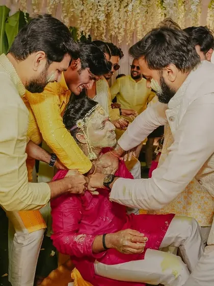 The groom's friends and family playfully apply Haldi paste during the ceremony.