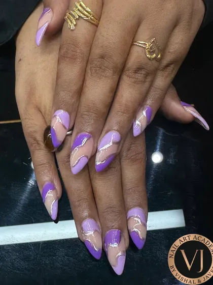 We created this elegant look on long, almond-shaped nails using shades of lavender and violet. The abstract swirls are accentuated with fine silver lines, creating a negative space design that is both modern and glamorous.