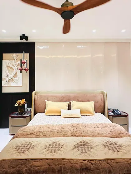 A full view of a cozy bedroom with a plush, brown upholstered bed and floor-to-ceiling wardrobes. The design is simple, elegant, and focused on comfort.