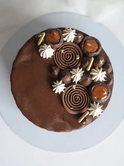 A top-down view of the Chocolate Caramel cake, highlighting the intricate decorations. The combination of dark chocolate and sweet, salty caramel is a classic for a reason.