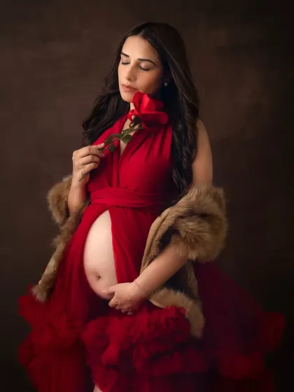 A classic and romantic fine art portrait. The rich red of the gown, the single rose, and the faux fur wrap create a look of timeless elegance and passion.