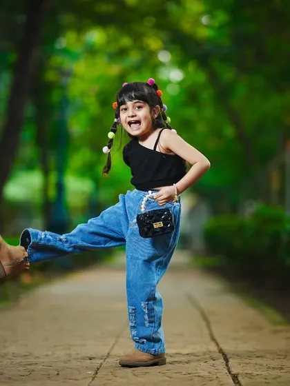 A fun, energetic shot of a little girl kicking up her heels on a park pathway. Outdoor shoots are perfect for capturing personality.
